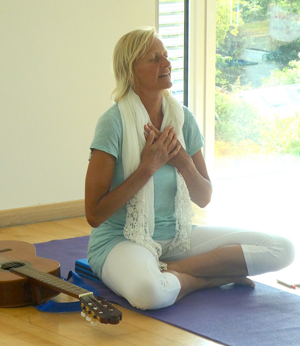 Woman in serene yoga pose with a guitar beside her.