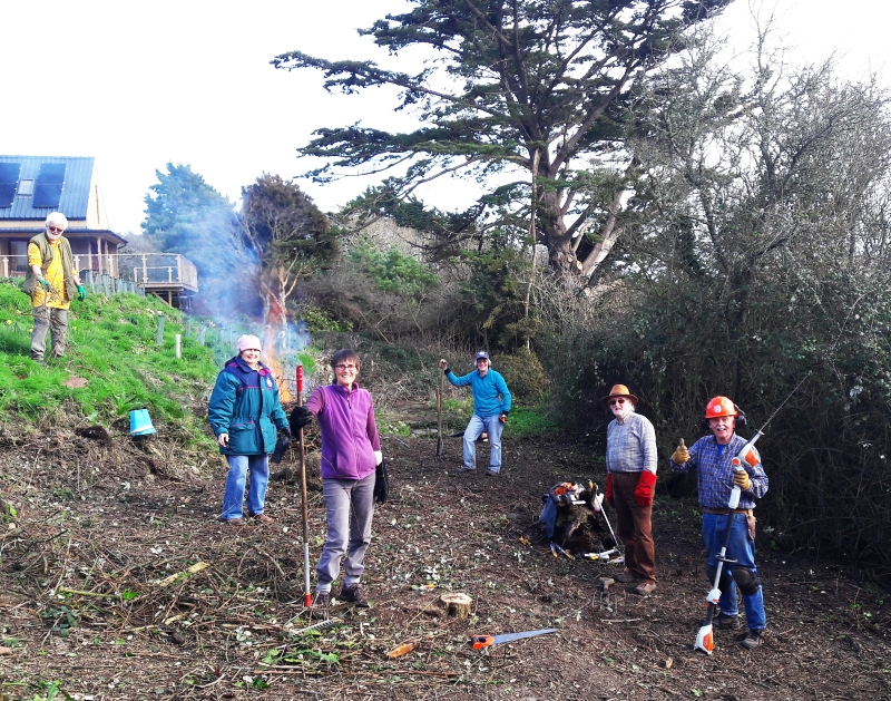 Volunteers clearing scrub, bonfire and Four Seasons Studio in background