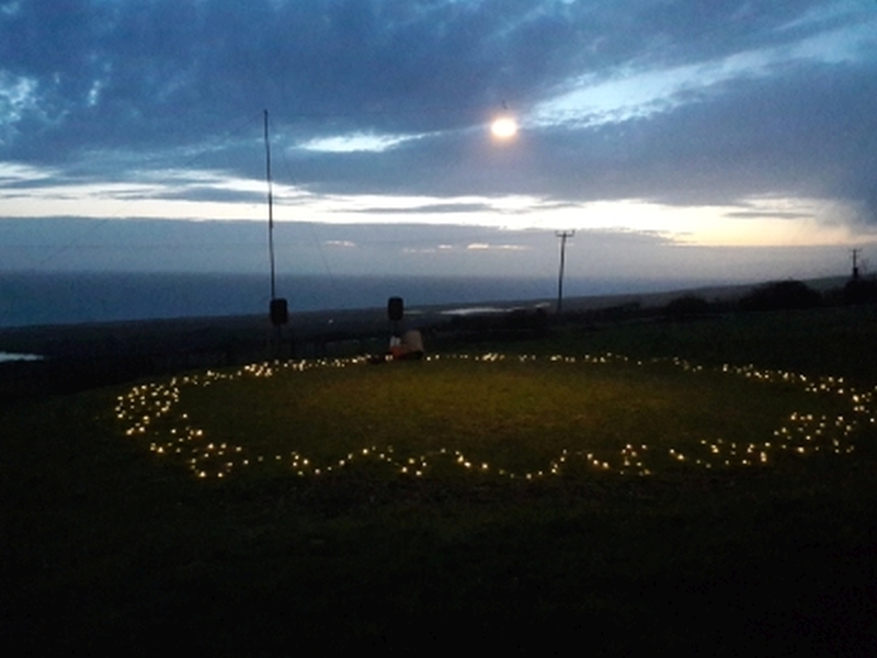 Dancing lawn circle with fairy lights, overlooking Lyme Bay at dusk