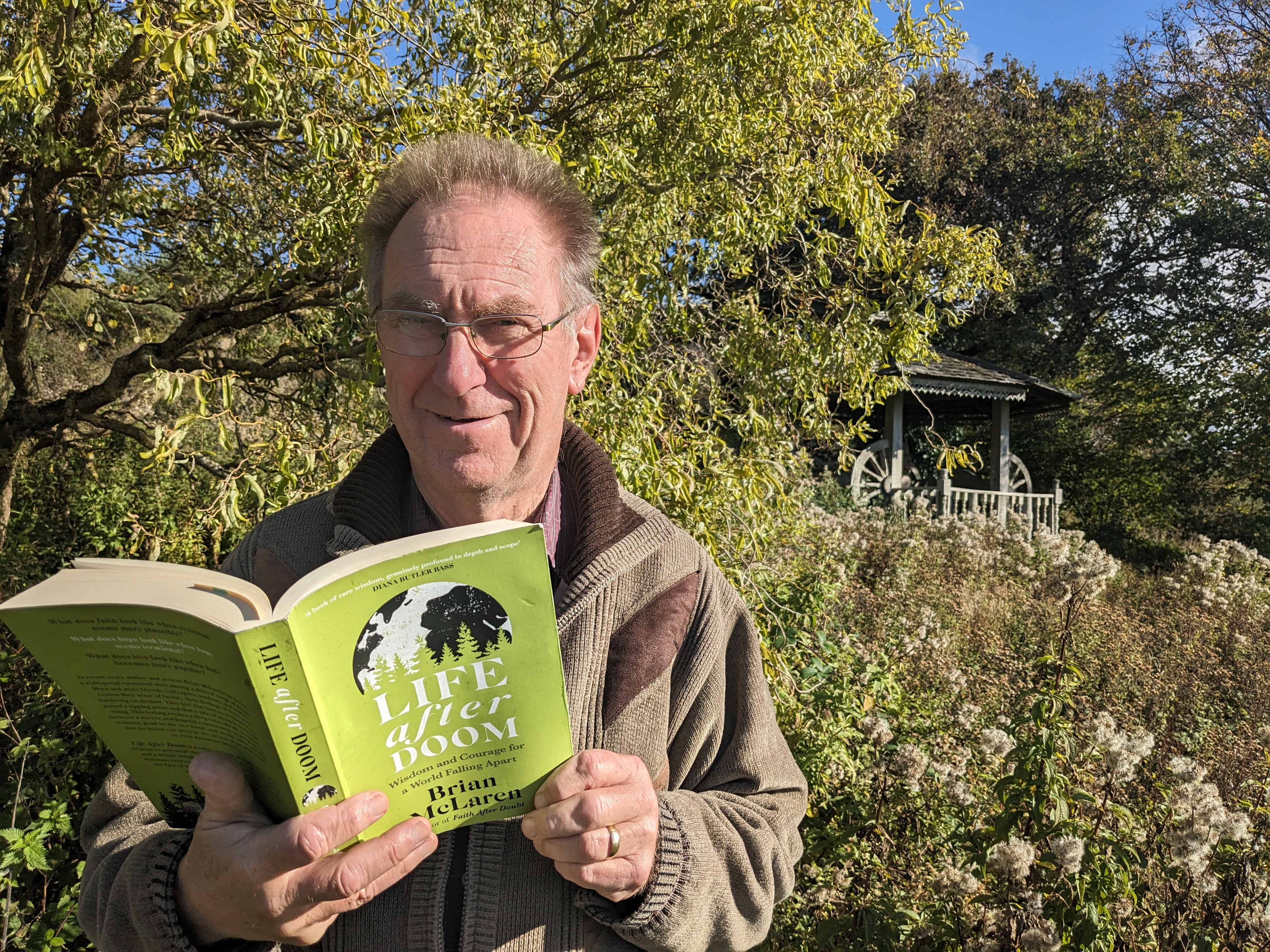 Tony Jaques outdoors at Othona with a copy of LIFE AFTER DOOM