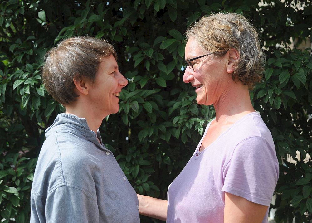 Two women standing face to face smiling at each other