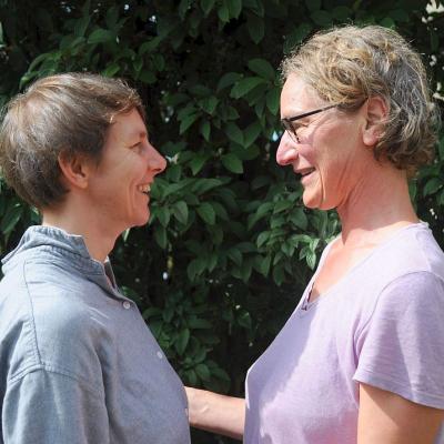 Two women standing face to face smiling at each other